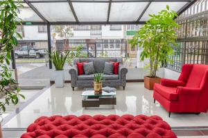 ein Wohnzimmer mit 2 Stühlen und einem roten Sofa in der Unterkunft Hotel Casa Quinta Embajada in Bogotá
