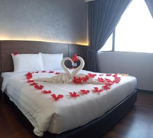 un lit avec deux cygnes dans un cœur fait de roses dans l'établissement Grace Hotel Semporna, à Semporna