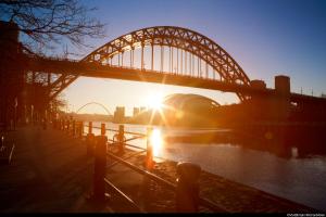 Holiday Inn Express Newcastle Gateshead, an IHG Hotel في نيوكاسل أبون تاين: جسر فوق نهر مع شروق الشمس تحته