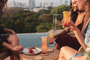 dos mujeres sentadas en una mesa con bebidas en Trillium Boutique City Hotel, en Colombo