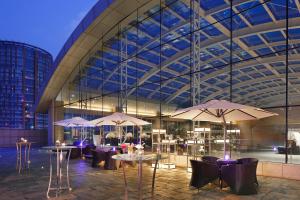 a restaurant with tables and umbrellas in front of a building at Crowne Plaza Beijing Lido, an IHG Hotel in Beijing
