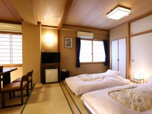 two beds in a room with a table and a desk at Ryokan Kamogawa Asakusa in Tokyo