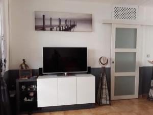 a living room with a flat screen tv on a white cabinet at chambre et table d’hôte au Diamant in Le Diamant