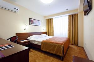 a hotel room with a bed and a desk at AZIMUT Hotel Kemerovo in Kemerovo