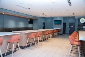 um bar num restaurante com bancos de bar laranja em Holiday Inn & Suites - Fayetteville W-Fort Bragg Area, an IHG Hotel em Fayetteville