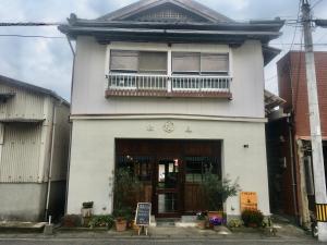 a white house with a balcony on top of it at Shioya Hostel in Akune