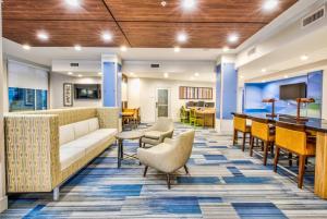 a lobby with a couch and chairs and a bar at Holiday Inn Express & Suites Dallas NW - Farmers Branch, an IHG Hotel in Farmers Branch