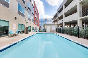 a large swimming pool in the courtyard of a building at Holiday Inn Express & Suites Dallas NW - Farmers Branch, an IHG Hotel in Farmers Branch