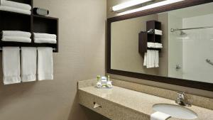 a bathroom with a sink and a mirror and towels at Holiday Inn Express & Suites Naples Downtown - 5th Avenue by IHG in Naples