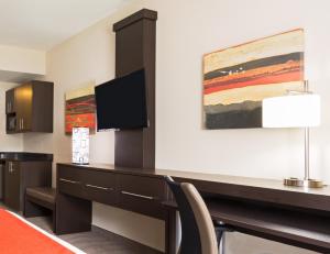 a hotel room with a desk and a tv at Holiday Inn Express & Suites Naples Downtown - 5th Avenue by IHG in Naples