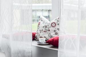 a window sill with pillows and a cup of coffee at Parkhotel FRITZ am Brunnen in Schwelm