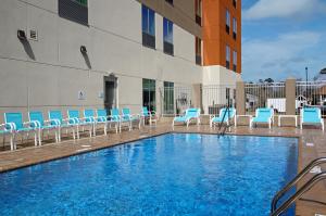 a swimming pool with blue chairs and a building at Holiday Inn Express & Suites - Lake Charles South Casino Area, an IHG Hotel in Lake Charles