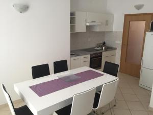 eine Küche mit einem weißen Tisch mit Stühlen und einem Tisch sowie eine Küche in der Unterkunft Apartment NOEL in Rogoznica