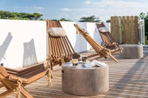a row of wooden chairs sitting on top of a wooden deck at Hôtel Océan in Capbreton