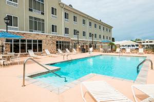 einen Pool in einem Hotel mit Stühlen und einem Gebäude in der Unterkunft Holiday Inn Express Hotel & Suites New Iberia - Avery Island, an IHG Hotel in New Iberia