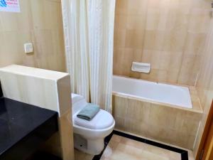 uma casa de banho com um WC branco e uma banheira em Tang Dynasty Hotel em Kota Kinabalu