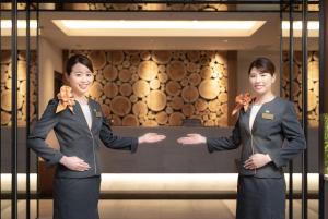 Due donne in giacca e cravatta davanti a un palazzo. di Super Hotel Yokohama Kannai a Yokohama