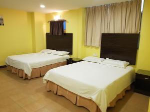 Duas camas num quarto com paredes amarelas em New City Hotel em Kajang