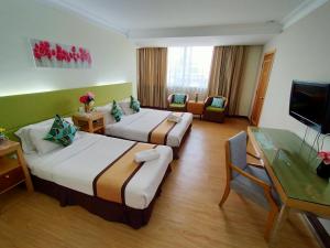 a hotel room with two beds and a television at Tang Dynasty Hotel in Kota Kinabalu