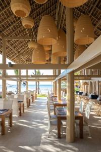 un restaurant avec des tables et des chaises et l'océan dans l'établissement VAYNA Boutique Koh Chang, à Ko Chang