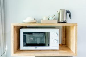 a microwave in a wooden shelf in a kitchen at Be Wish Residence in Bangkok