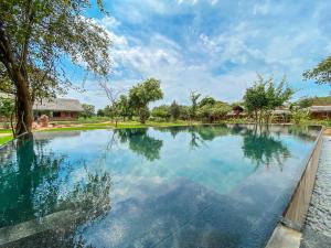 una piscina en un complejo con árboles y nubes en el cielo en Ayurvie Sigiriya - Ayurvedic Retreat by Thema Collection en Sigiriya