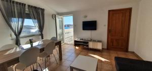 a living room with a table and chairs and a television at Apartments Kolak in Rogoznica
