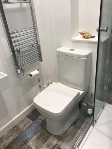 a white bathroom with a toilet and a shower at Daisy Cottage in Saint Monance