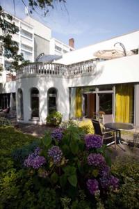 uma casa branca com varanda e flores roxas em Residenz Am Malerwinkel em Bad Sassendorf