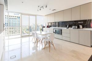 a kitchen with white cabinets and a table and chairs at Stella Stays Stunning & Luxurious 4BDR Penthouse Dubai Marina in Dubai