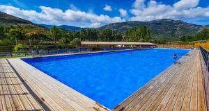a large blue swimming pool with mountains in the background at Camping Le Sagone in Sagone