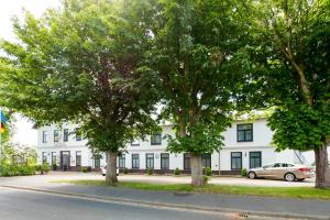 um edifício branco com árvores em frente em Golf- & Landhotel am alten Deich em Büsum