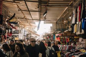 a crowd of people walking through a market at King's Rooftop Studios in Tel Aviv