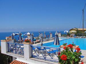 a swimming pool with chairs and umbrellas and the ocean at Lido Sofia Apartments in Agios Gordios