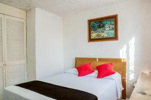 Capital O Farallon Inn, Cancún في كانكون: غرفة نوم بسريرين ومخدات حمراء
