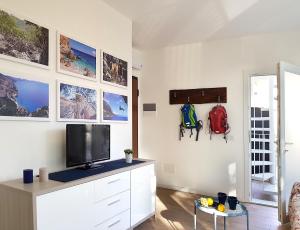een woonkamer met een tv aan een witte muur bij Casa Olivastro Vista Mare in Santa Maria Navarrese