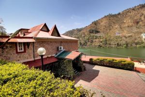 ein Gebäude neben einem See mit einem Berg in der Unterkunft Neelesh Inn- A Luxury Lake View Hotel- 20 kms from Nainital in Bhīm Tāl