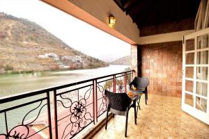 einen Balkon mit Stühlen und Flussblick in der Unterkunft Neelesh Inn- A Luxury Lake View Hotel- 20 kms from Nainital in Bhīm Tāl