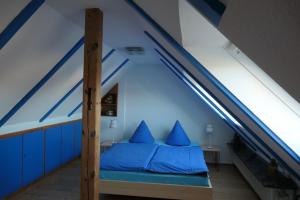 um quarto com uma cama com almofadas azuis num sótão em "Haus am Deich" em Cuxhaven
