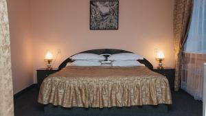 - une chambre avec un grand lit et deux lampes de chaque côté dans l'établissement Aktobe Hotel, à Aqtöbe