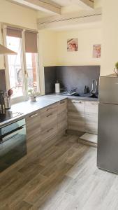 a kitchen with wooden floors and a stainless steel refrigerator at Le Familial in Kintzheim