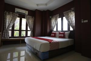 a bedroom with a bed in a room with windows at Yellow Tique Hotel in Lampang