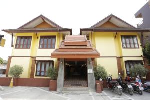 um edifício amarelo com motos estacionadas em frente em Yellow Tique Hotel em Lampang