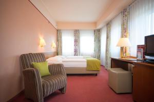 a hotel room with a bed and a chair at Trip Inn PostHotel Düren in Düren - Eifel