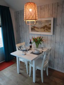 een witte eettafel met stoelen en een kroonluchter bij Vakantiewoning Akkerrand Kamperland in Kamperland