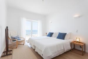 a white bedroom with two beds and a window at Blue Buddha Beach Rooms & Suites in Ericeira