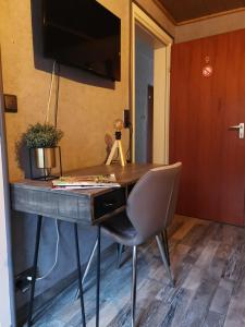 a desk with a chair and a television on a wall at Pension Abshoff in Meschede