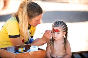 a young girl getting her face painted by a woman at Amwaj Oyoun Resort & Casino in Sharm El Sheikh