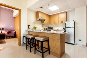 a kitchen with a bar with stools and a refrigerator at Staycae Holiday Homes - Suburbia, Jebel Ali in Dubai