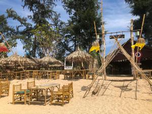 una spiaggia con sedie, tavoli e ombrelloni di paglia di Lanta Palm Beach Resort , Beach Bungalow - Koh Lanta a Ko Lanta Altre 58 foto